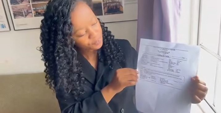 Lutho holding up a building plan approval notification in the noh Architects office