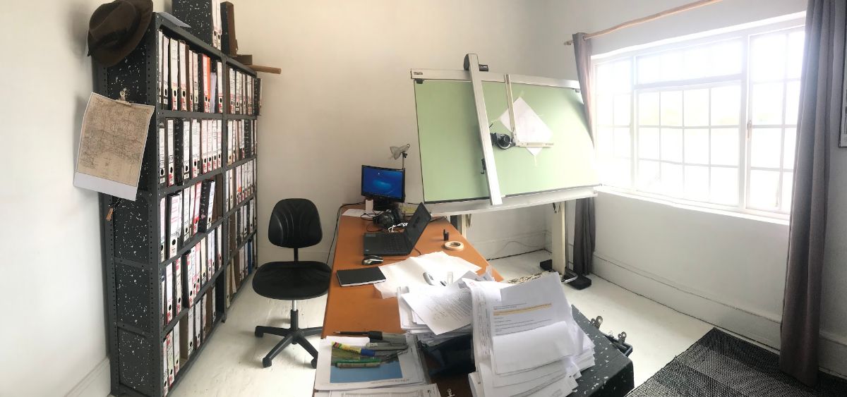 Lever-arch files, a drafting board and a desk that clearly needs filing